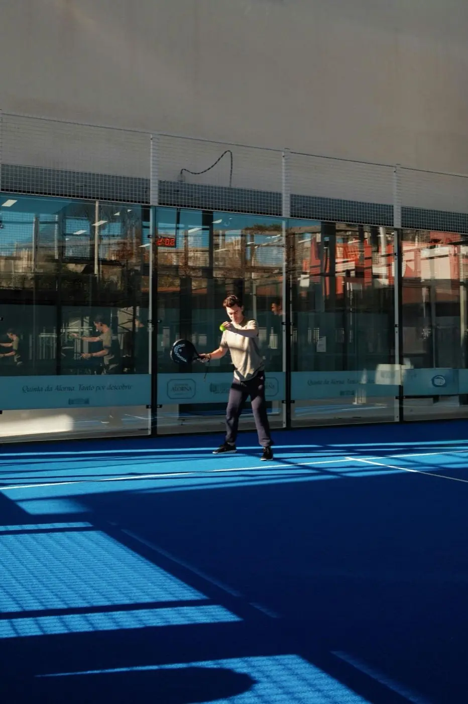Padel player swinging on a sun-lit outdoor court